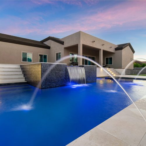 Laminar jets arcing over a pool at dusk on Brooks Farm Road in Gilbert, AZ by Envy Pools