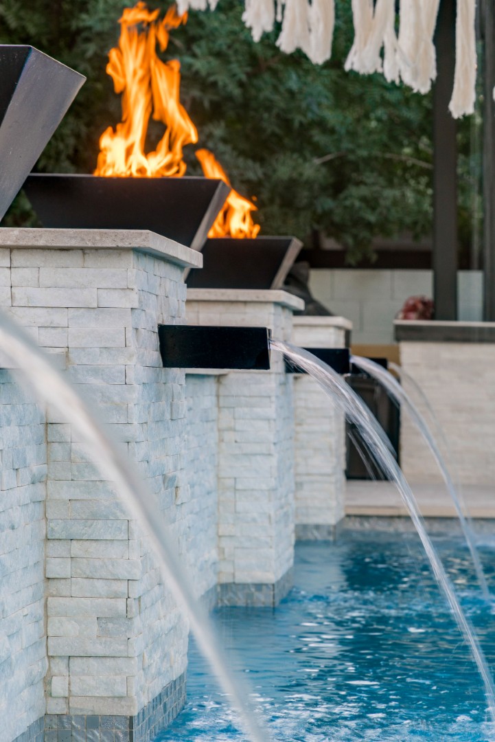 Custom pool with fire bowls, glass curtain waterfall, and outdoor kitchen in Queen Creek, AZ by Envy Pools