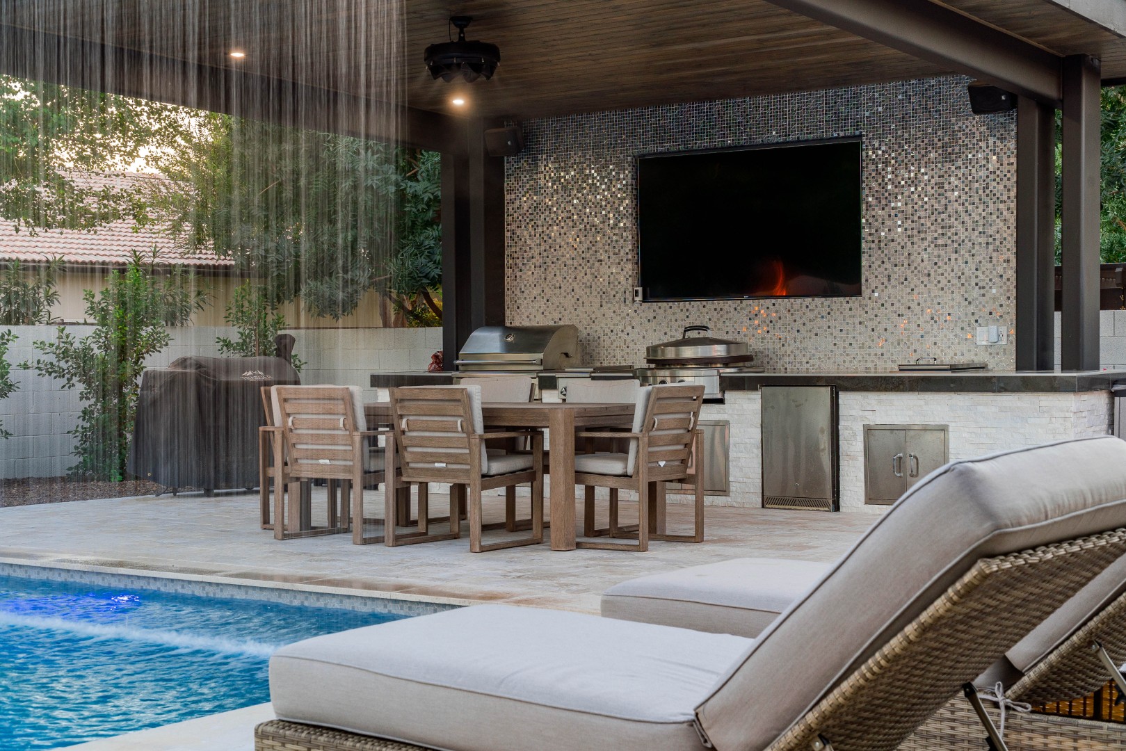 Custom pool with fire bowls, glass curtain waterfall, and outdoor kitchen in Queen Creek, AZ by Envy Pools