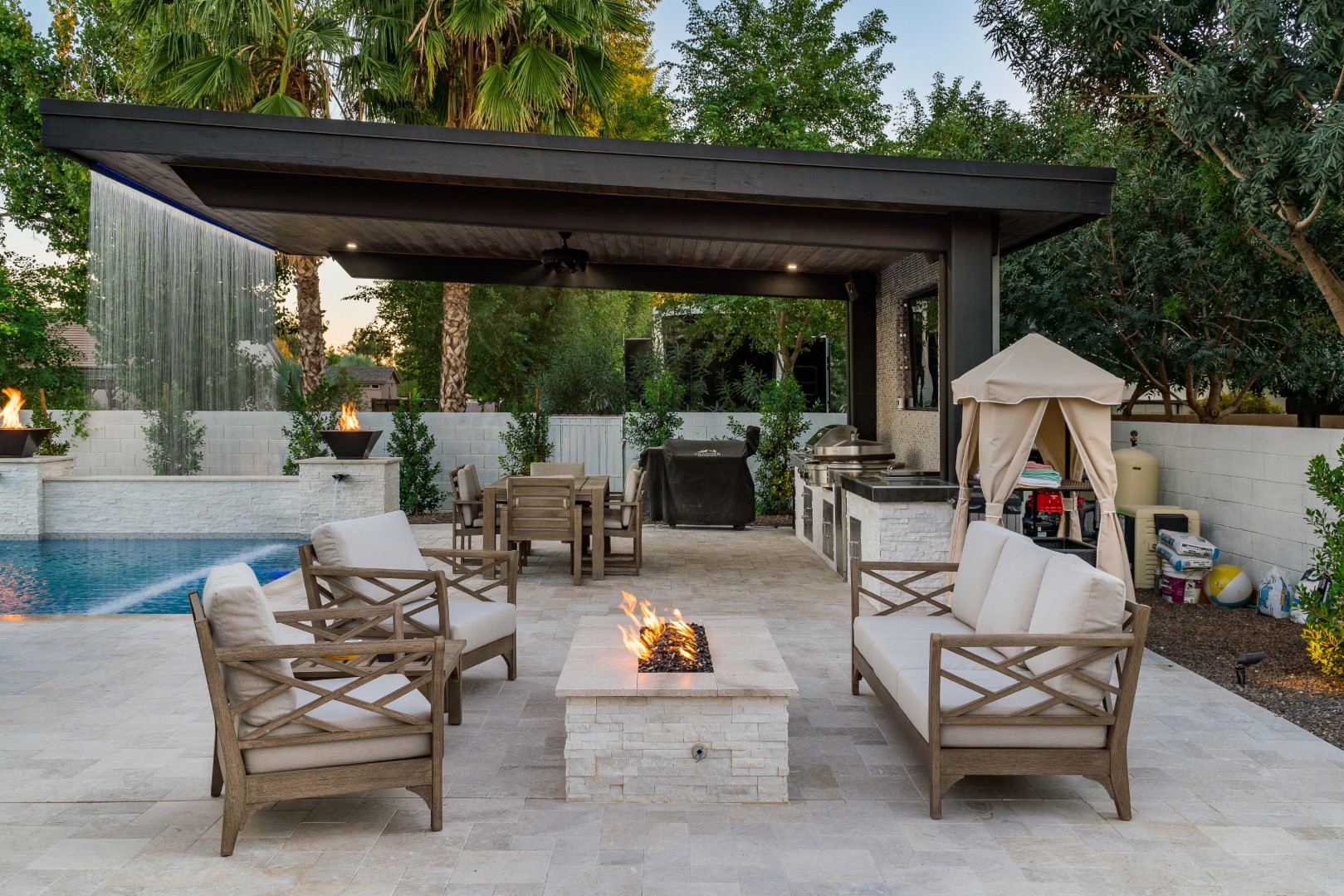 Custom pool with fire bowls, glass curtain waterfall, and outdoor kitchen in Queen Creek, AZ by Envy Pools