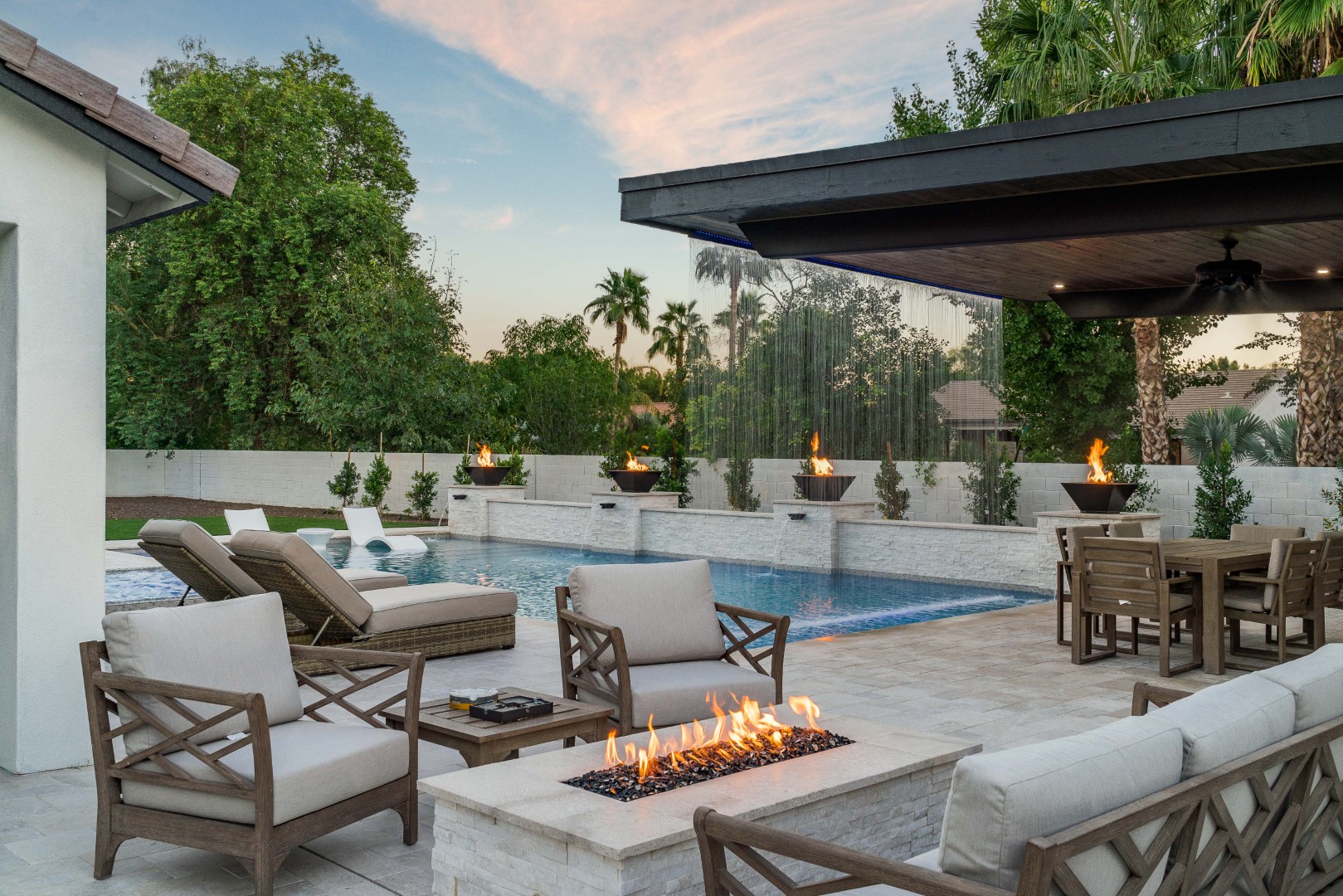 Custom pool with fire bowls, glass curtain waterfall, and outdoor kitchen in Queen Creek, AZ by Envy Pools