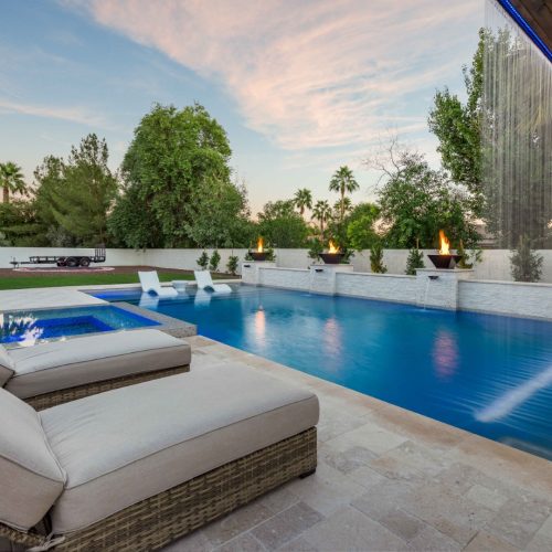 Custom pool with fire bowls, glass curtain waterfall, and outdoor kitchen in Queen Creek, AZ by Envy Pools