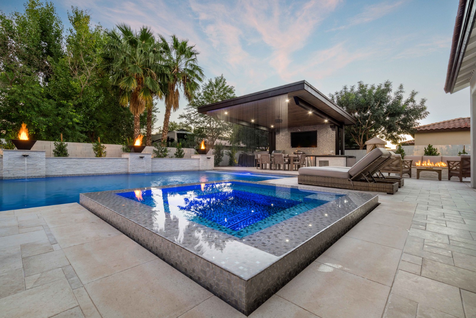 Custom pool with fire bowls, glass curtain waterfall, and outdoor kitchen in Queen Creek, AZ by Envy Pools