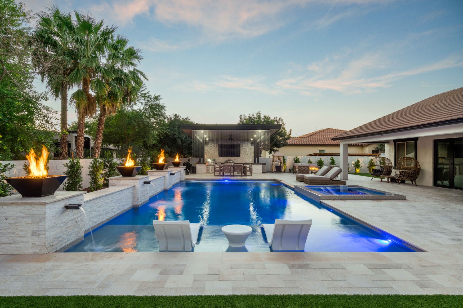 Custom pool with fire bowls, glass curtain waterfall, and outdoor kitchen in Queen Creek, AZ by Envy Pools