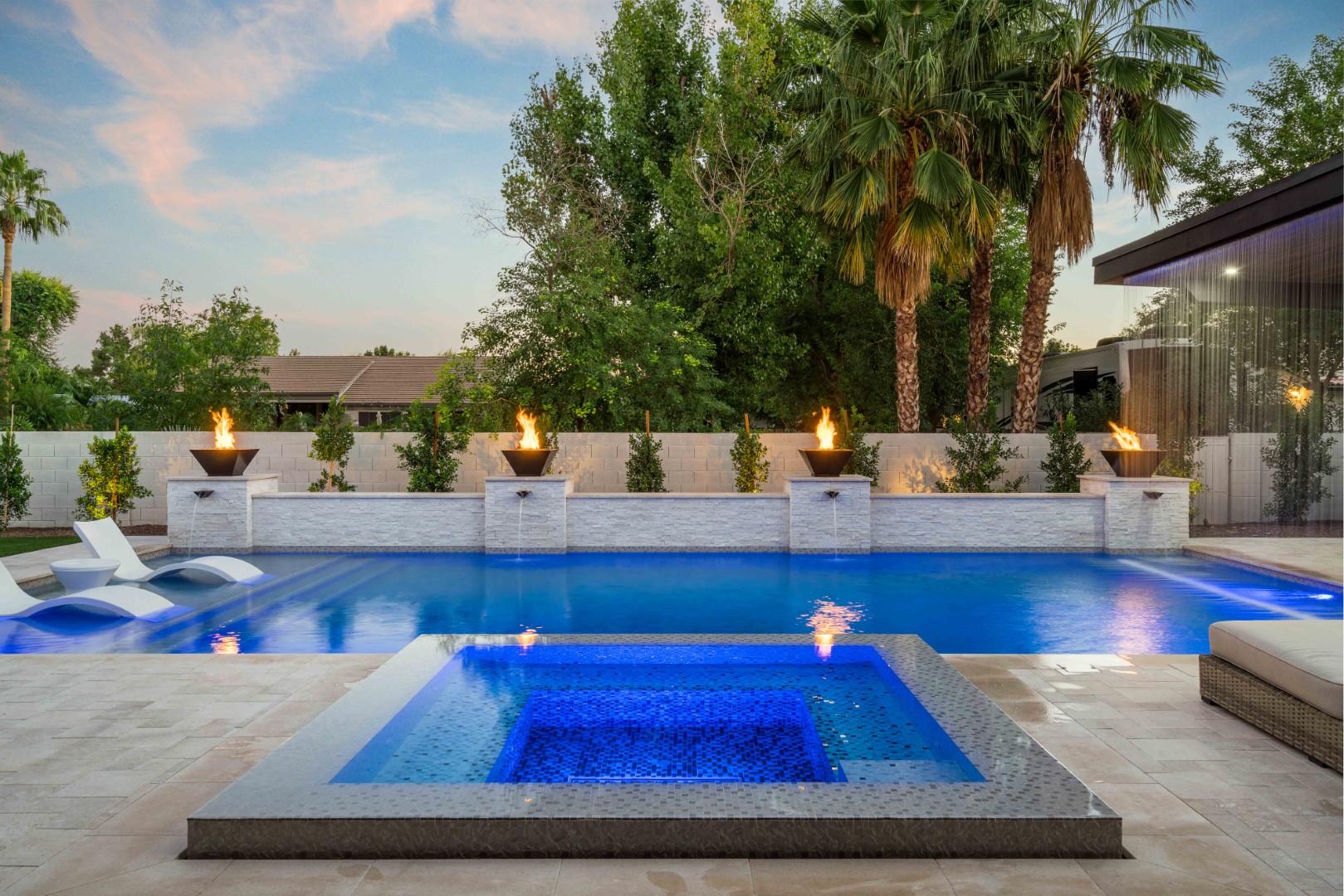 Custom pool with fire bowls, glass curtain waterfall, and outdoor kitchen in Queen Creek, AZ by Envy Pools