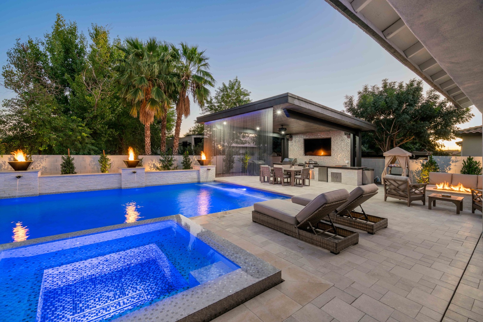 Custom pool with fire bowls, glass curtain waterfall, and outdoor kitchen in Queen Creek, AZ by Envy Pools