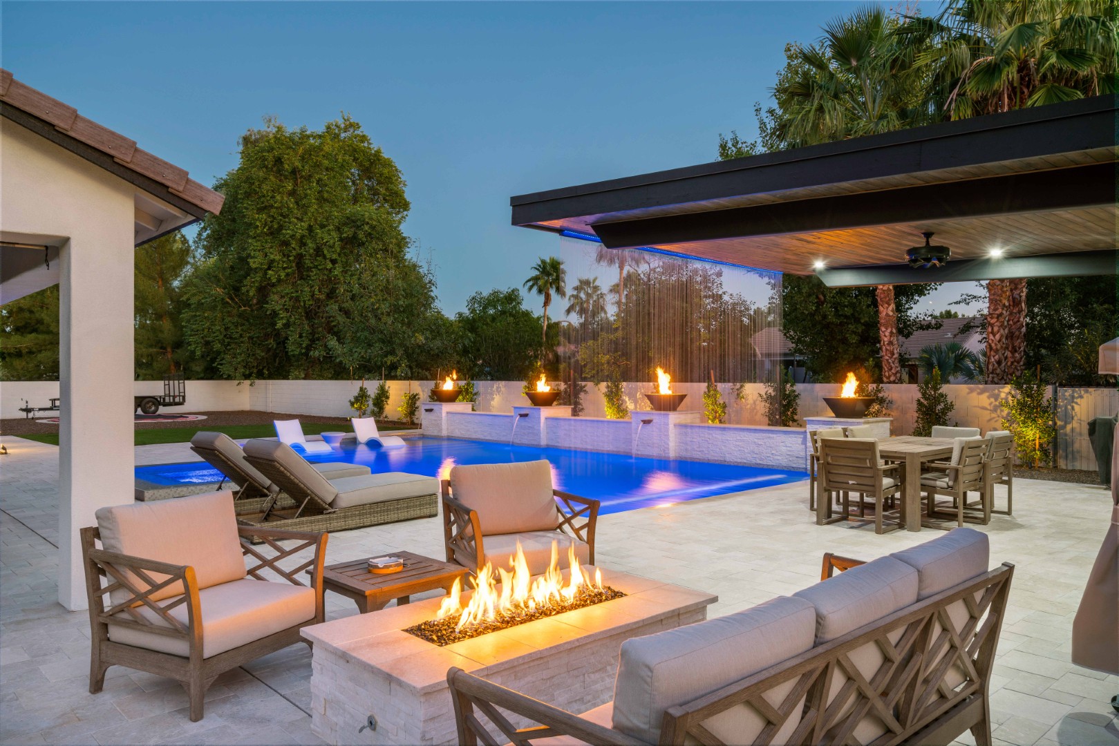 Custom pool with fire bowls, glass curtain waterfall, and outdoor kitchen in Queen Creek, AZ by Envy Pools