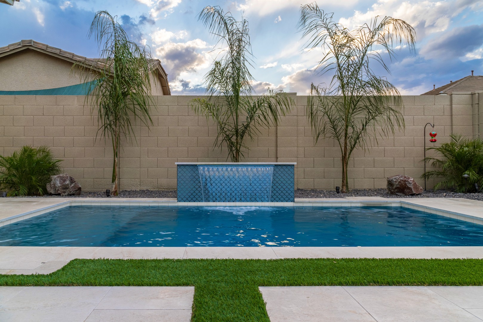 Custom rectangular pool with fish-scale tile water feature and fire pit in Gilbert, AZ by Envy Pools