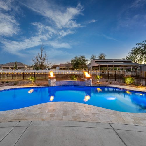 Freeform pool and travertine deck at dusk on Pummerlos Road in Queen Creek, AZ by Envy Pools