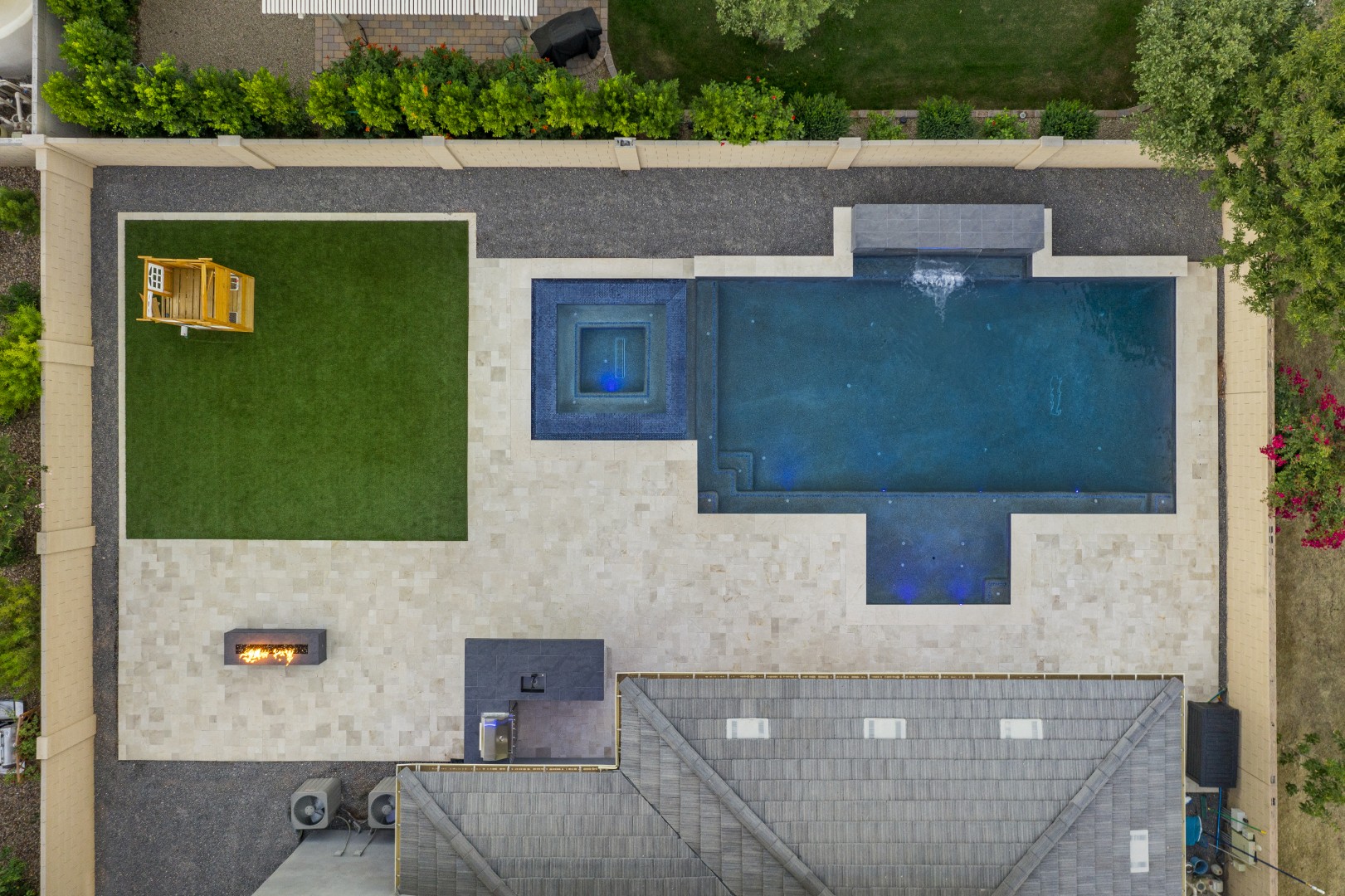 Custom pool with fire and water feature wall, raised spa, and outdoor kitchen in Gilbert, AZ by Envy Pools
