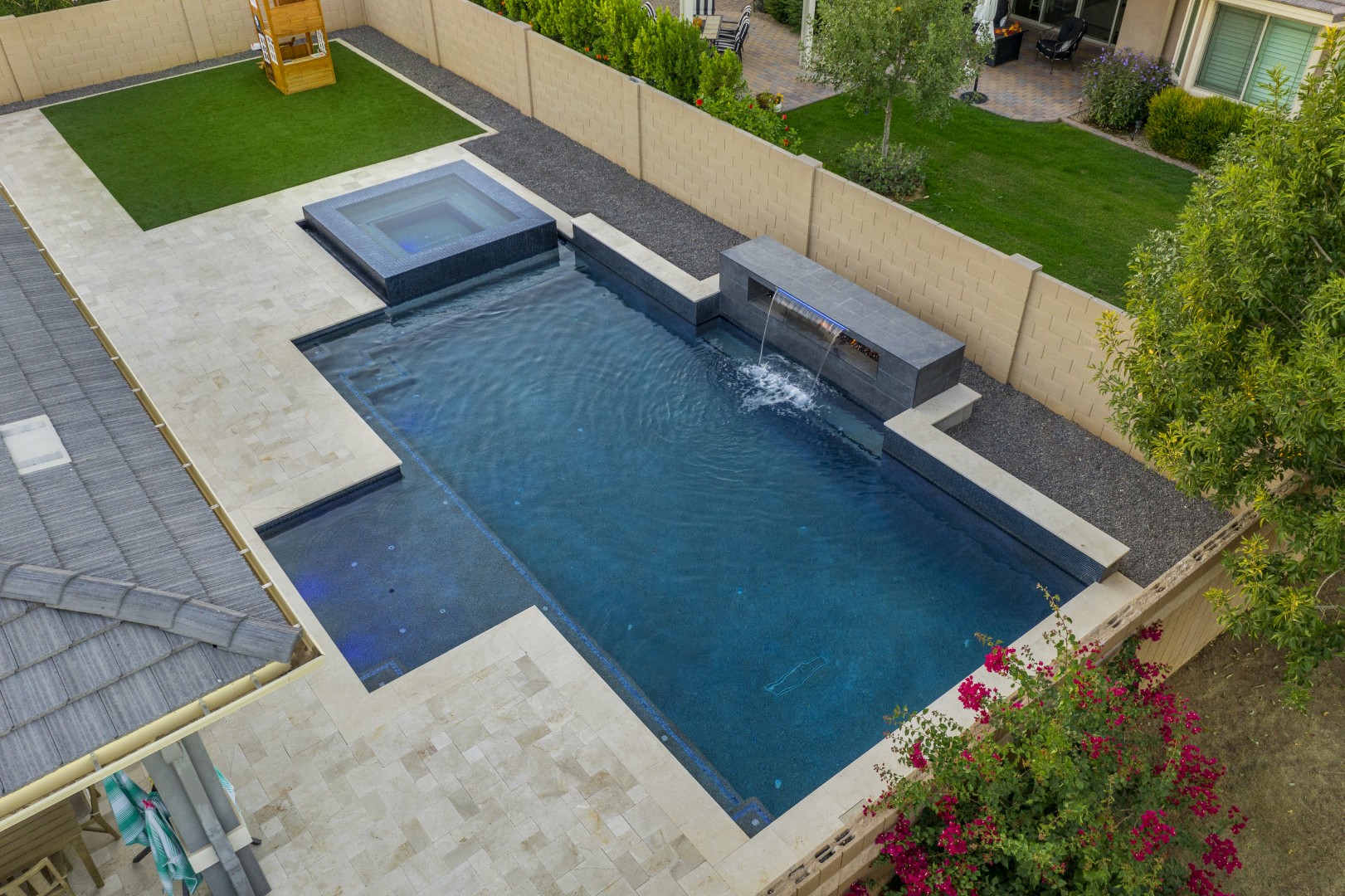 Custom pool with fire and water feature wall, raised spa, and outdoor kitchen in Gilbert, AZ by Envy Pools