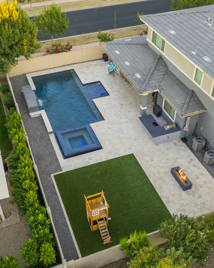 Custom pool with fire and water feature wall, raised spa, and outdoor kitchen in Gilbert, AZ by Envy Pools