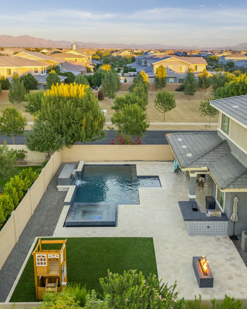 Custom pool with fire and water feature wall, raised spa, and outdoor kitchen in Gilbert, AZ by Envy Pools