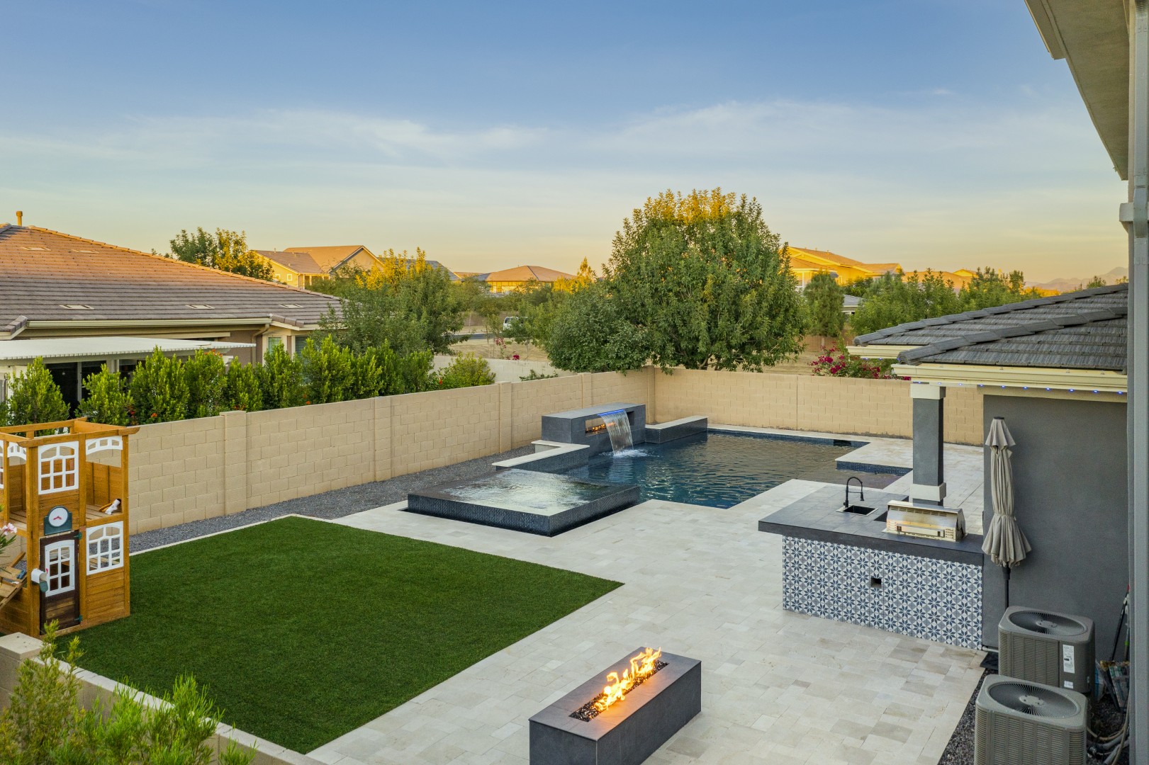 Custom pool with fire and water feature wall, raised spa, and outdoor kitchen in Gilbert, AZ by Envy Pools