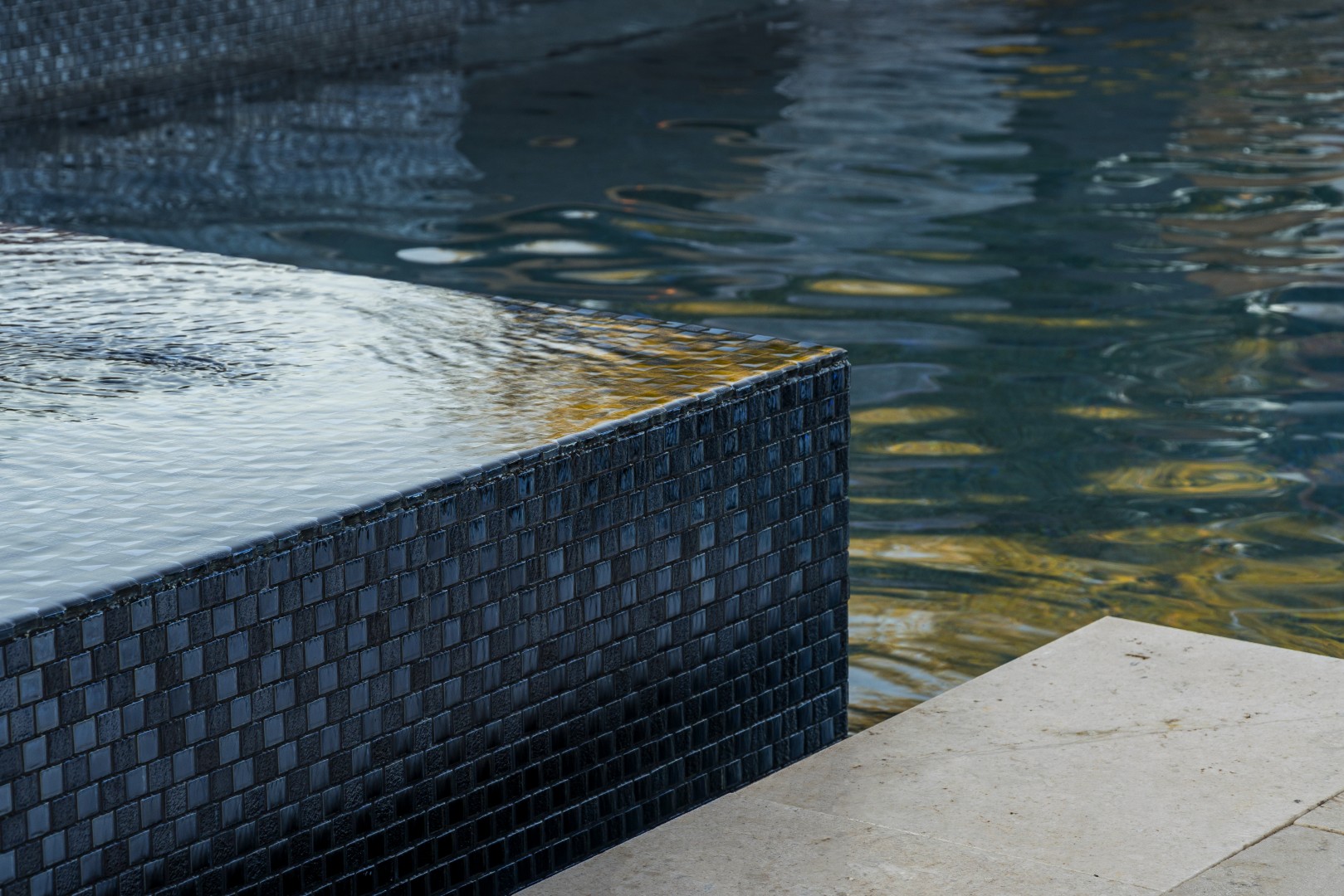 Custom pool with fire and water feature wall, raised spa, and outdoor kitchen in Gilbert, AZ by Envy Pools