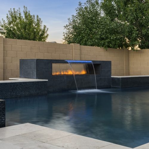 Custom pool with fire and water feature wall, raised spa, and outdoor kitchen in Gilbert, AZ by Envy Pools