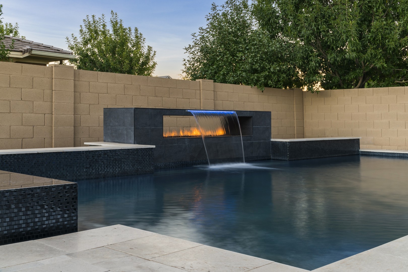 Custom pool with fire and water feature wall, raised spa, and outdoor kitchen in Gilbert, AZ by Envy Pools