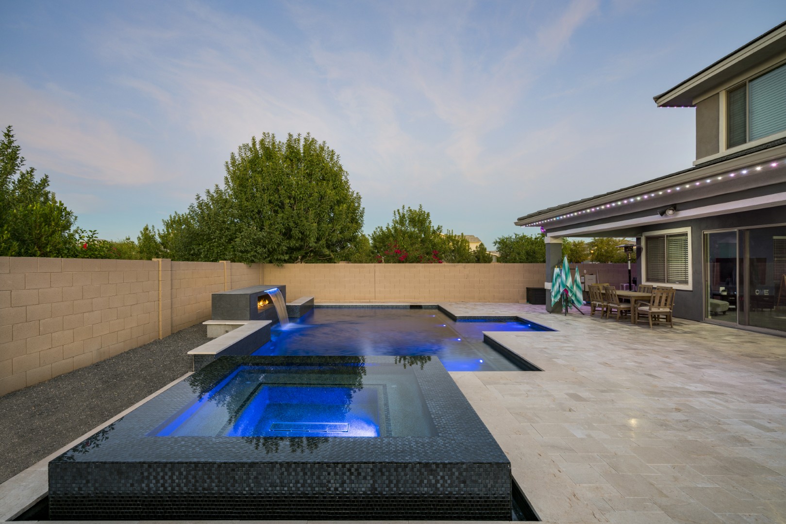 Custom pool with fire and water feature wall, raised spa, and outdoor kitchen in Gilbert, AZ by Envy Pools