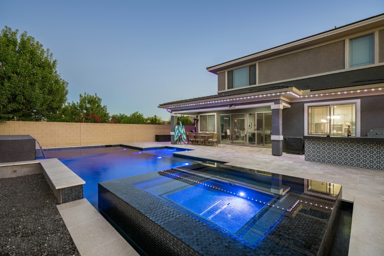 Custom pool with fire and water feature wall, raised spa, and outdoor kitchen in Gilbert, AZ by Envy Pools