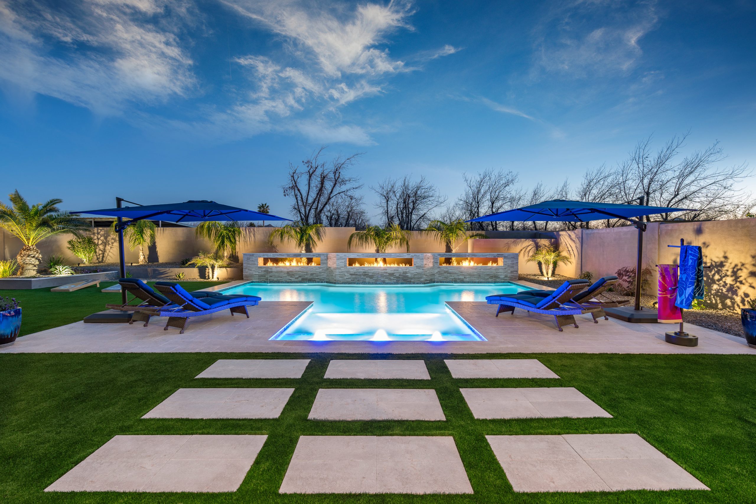 Pool with sun shelf and turf decking at dusk in Queen Creek, AZ