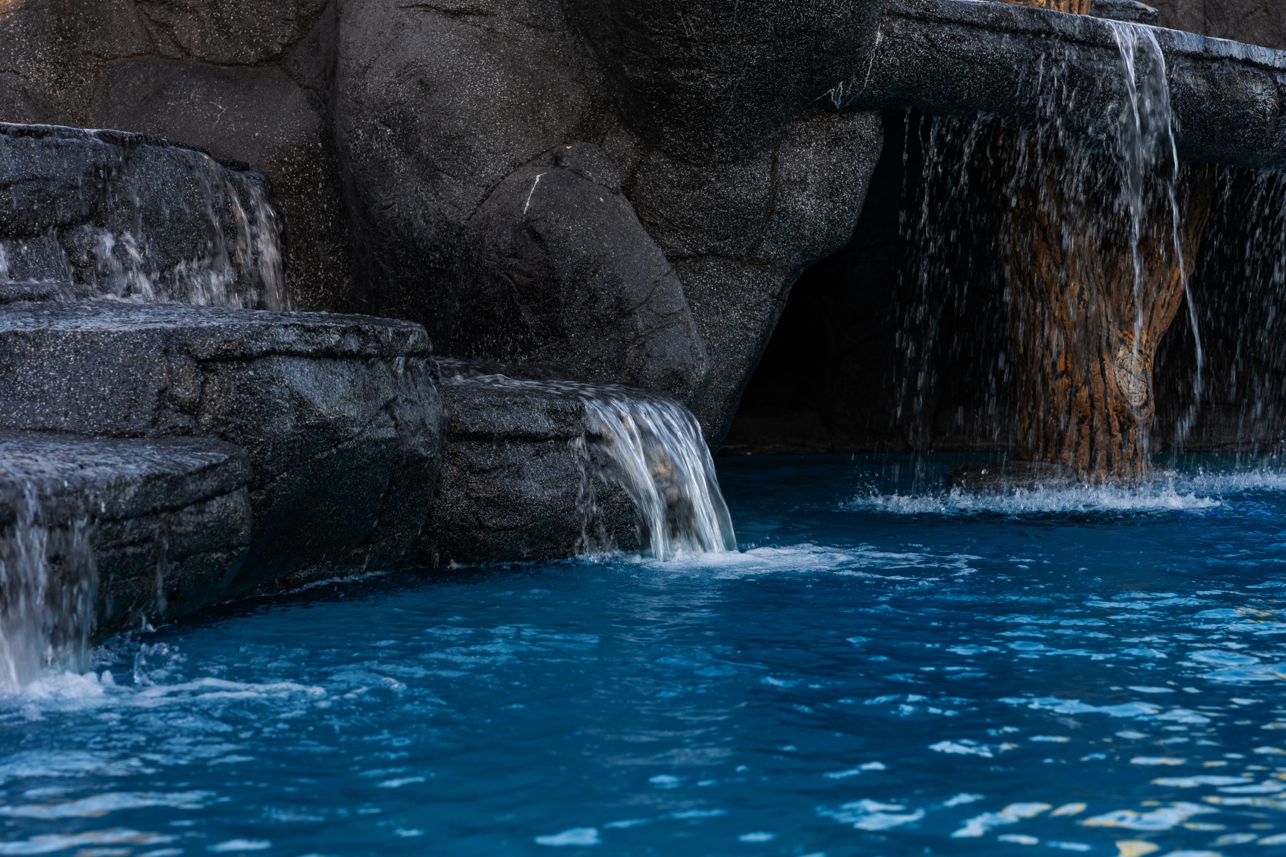 Stepped rock waterfall spilling into a blue freeform pool in Gilbert, AZ