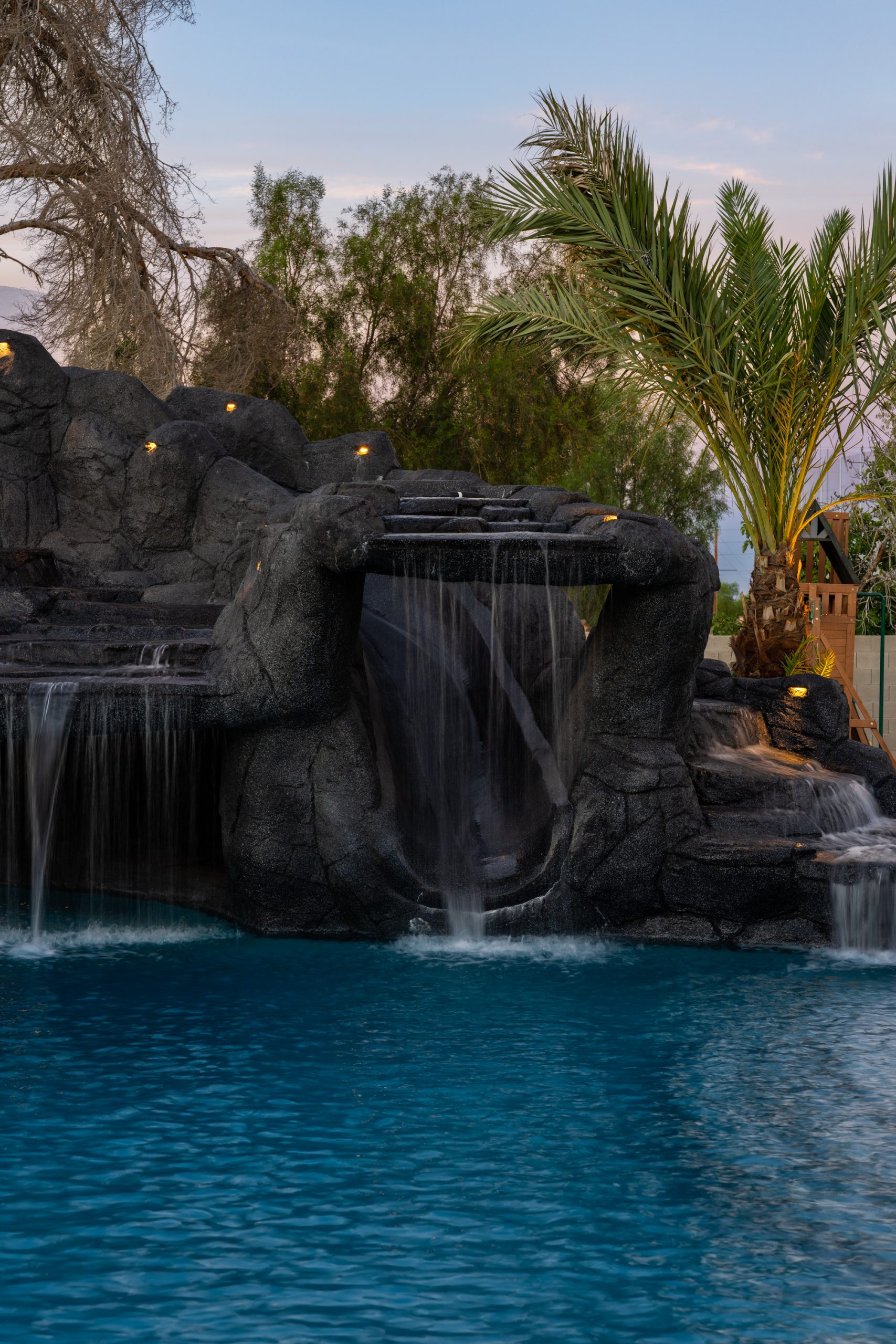 Rock waterfall and freeform pool at dusk in Gilbert, AZ