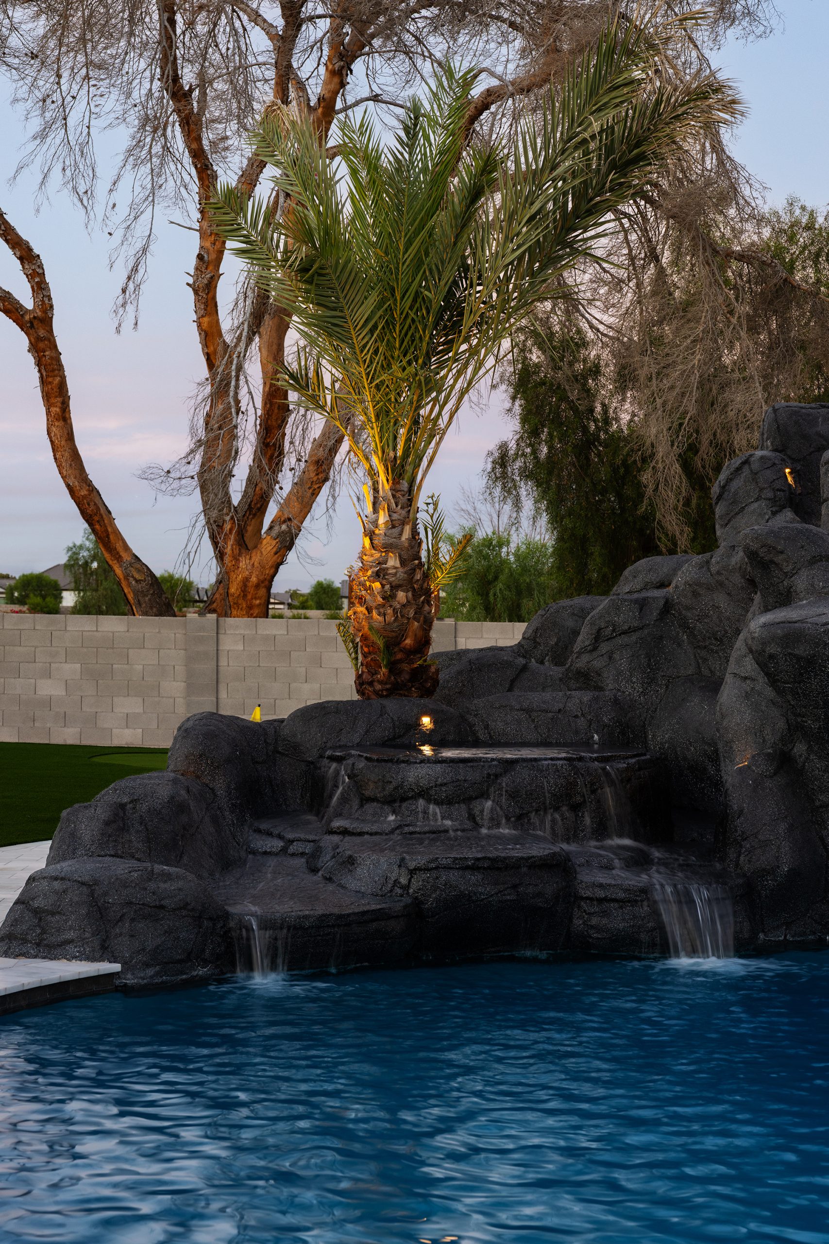 Palm-lined rock water feature beside a custom pool in Gilbert, AZ