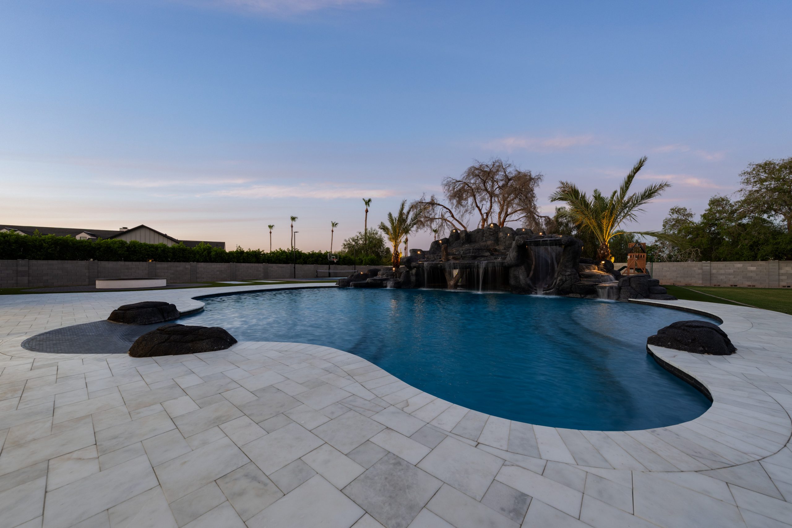 Freeform pool with boulder accents and travertine decking in Gilbert, AZ