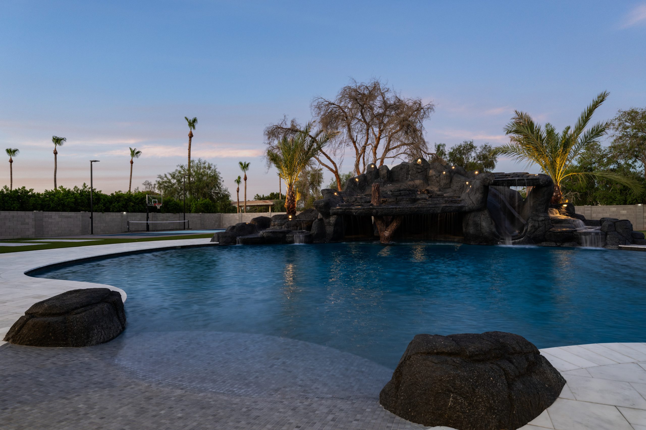 Custom pool and rock waterfall at sunset in Gilbert, AZ