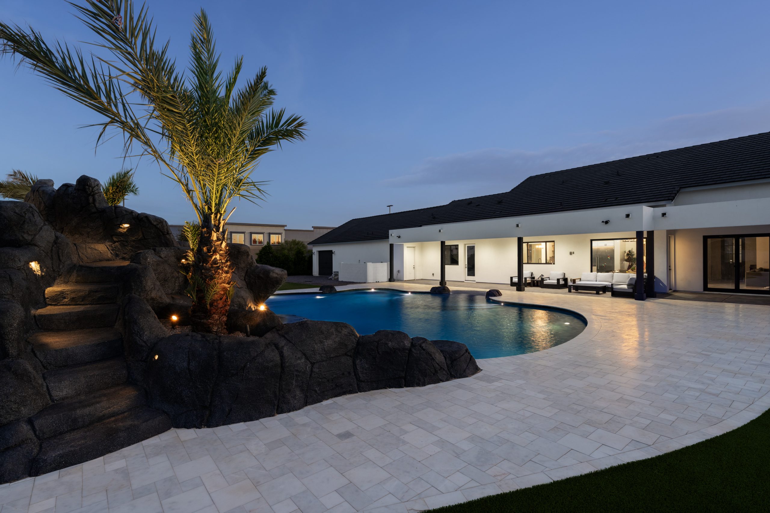 Rock waterfall, palms and pool lighting in a Gilbert, AZ backyard