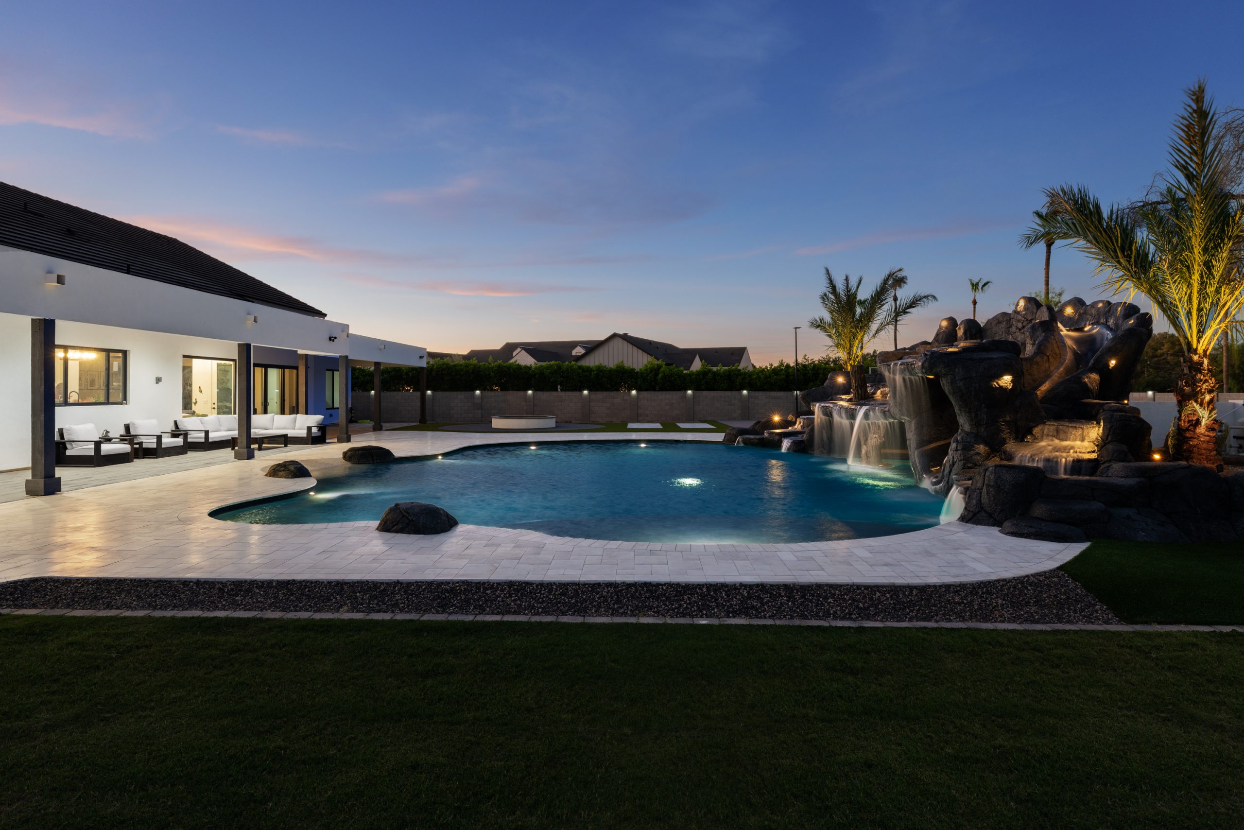 Modern home and custom freeform pool lit at dusk in Gilbert, AZ