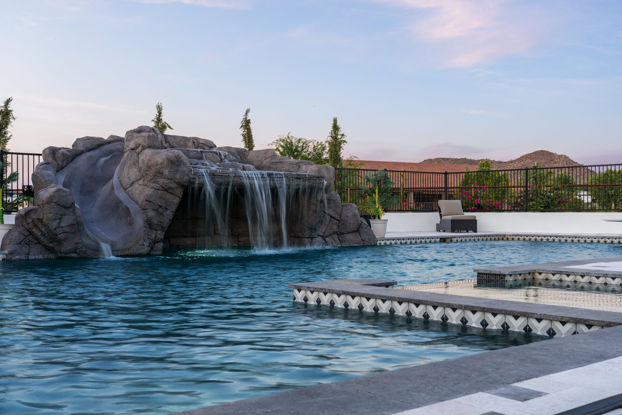 Rock waterfall grotto spilling into a custom pool in San Tan Valley, AZ