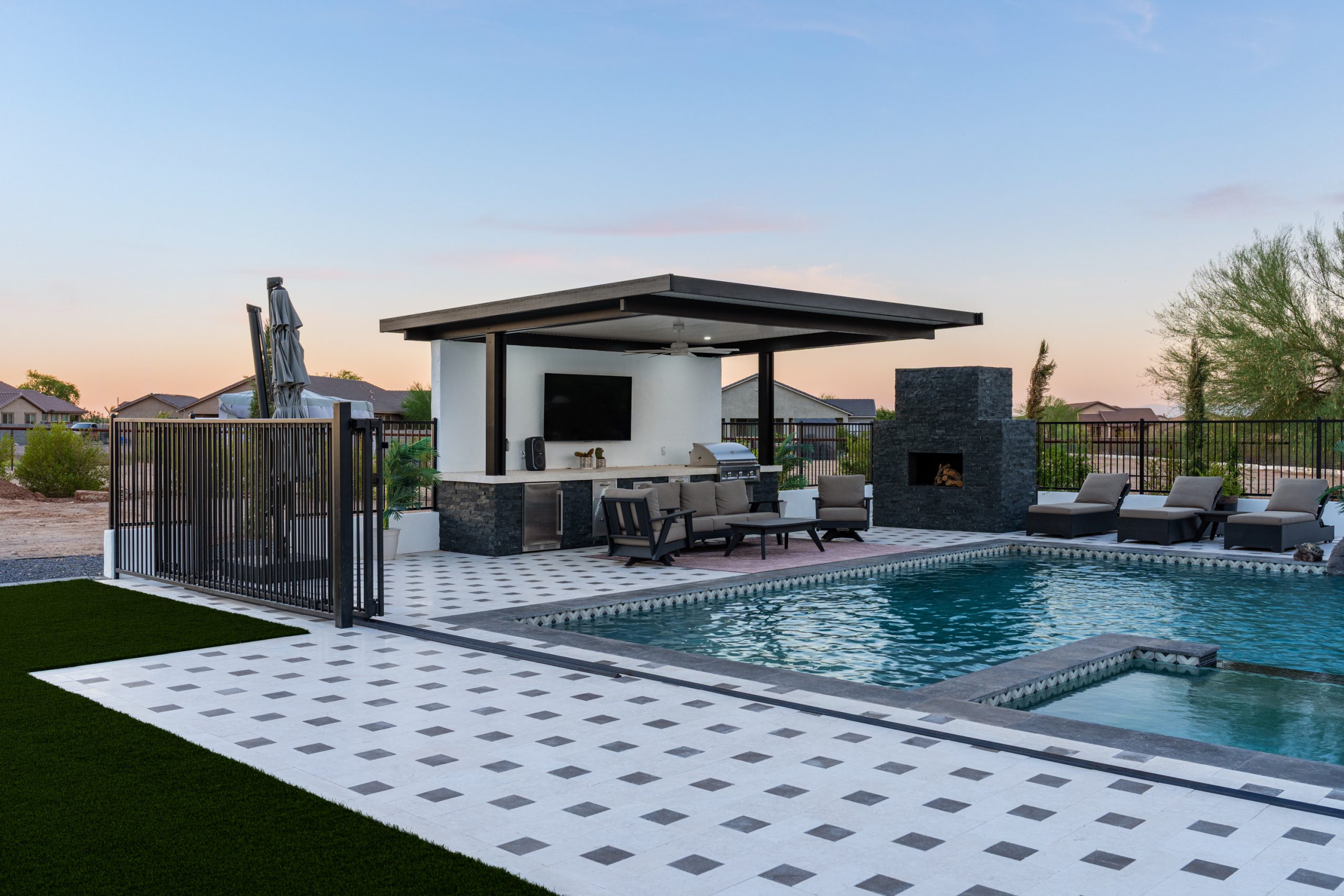 Pergola with outdoor kitchen and fireplace beside a pool in San Tan Valley, AZ