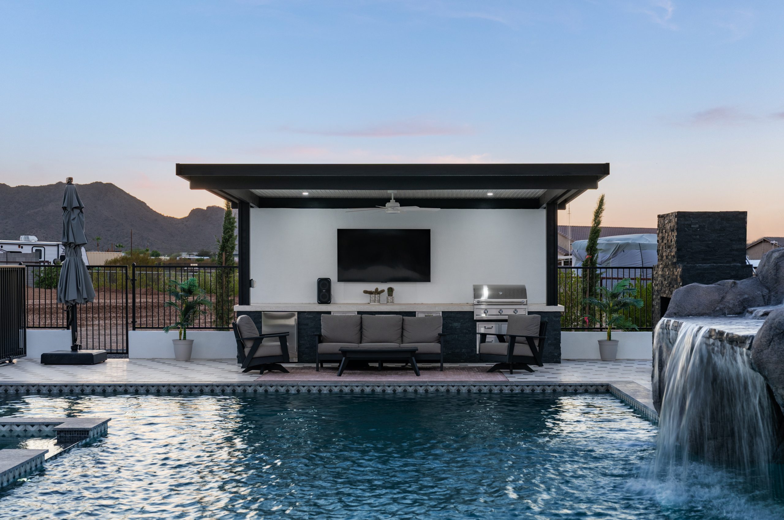 Poolside pergola with mounted TV and bar seating in San Tan Valley, AZ
