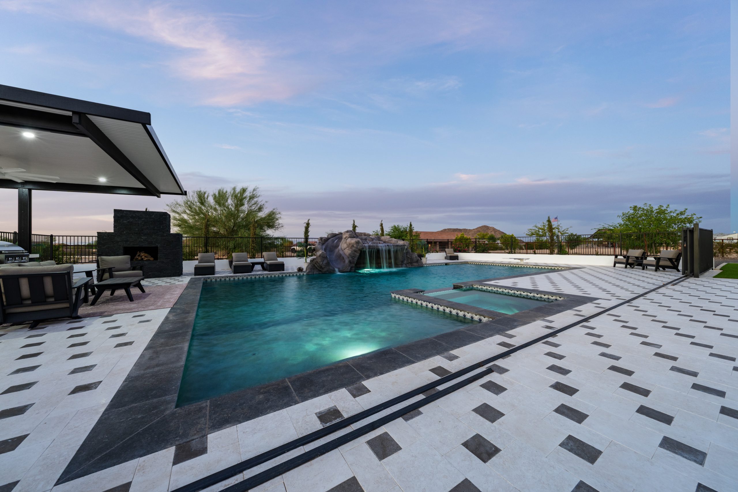 Custom pool, pergola and fireplace lit at dusk in San Tan Valley, AZ