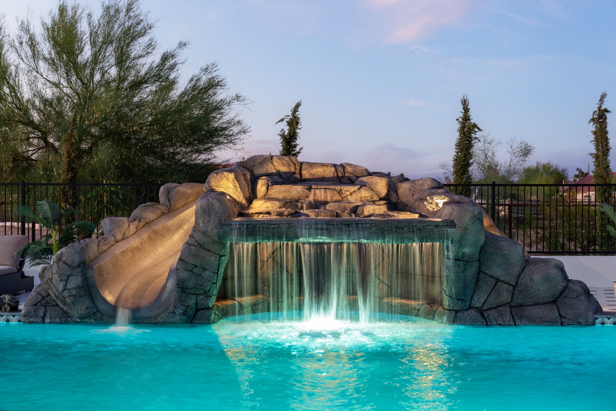 Rock waterfall lit at night over a custom pool in San Tan Valley, AZ