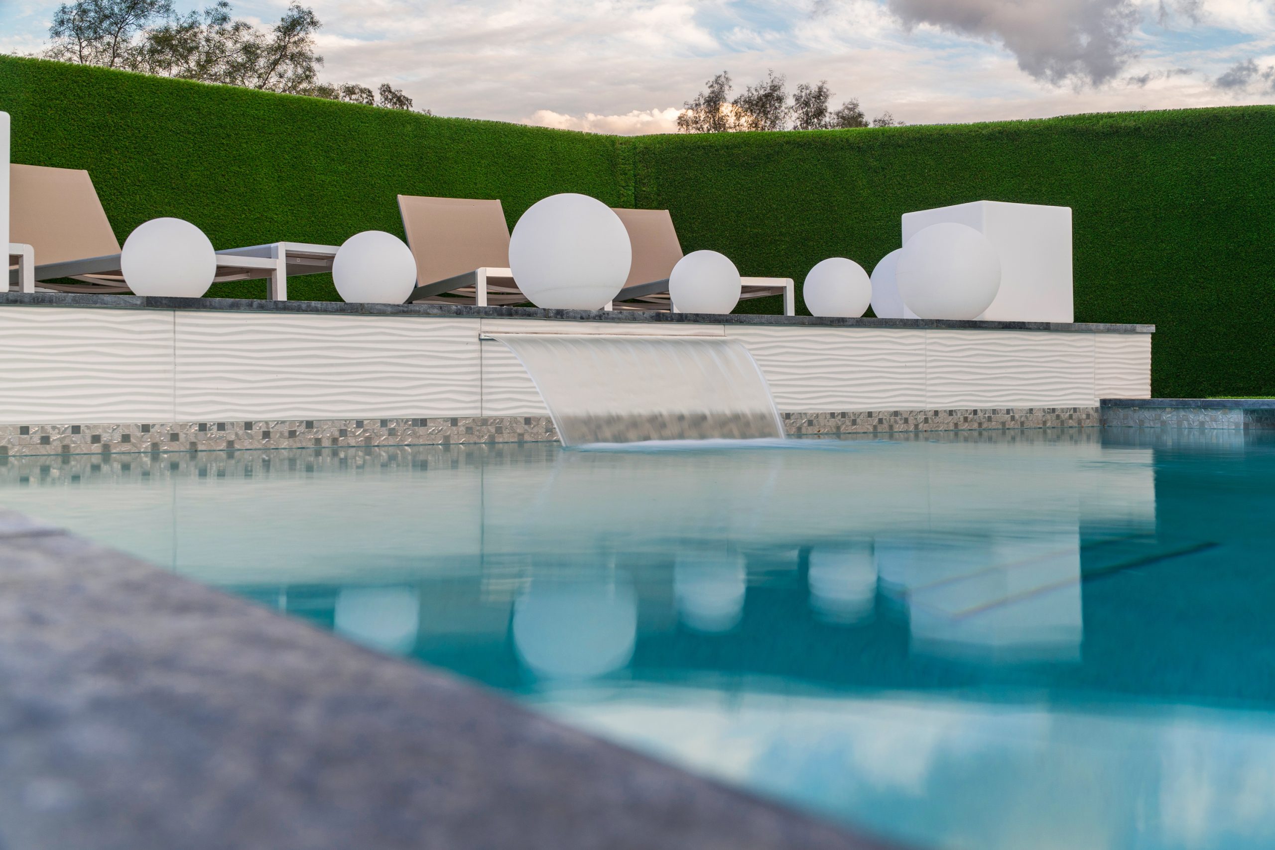 Sheer descent water feature spilling into a modern rectangular pool in Scottsdale, AZ