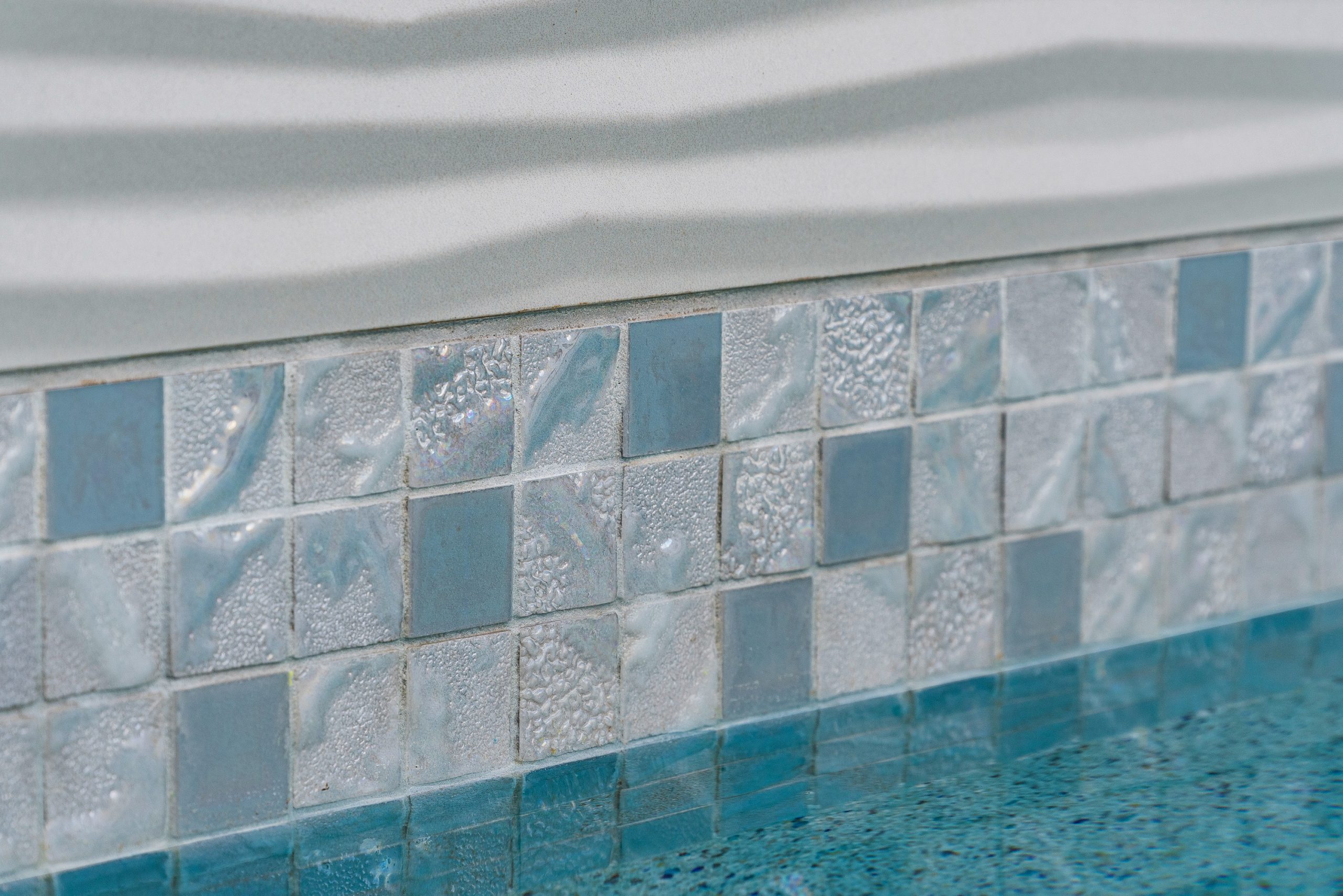 Iridescent glass mosaic waterline tile detail on a custom pool in Scottsdale, AZ