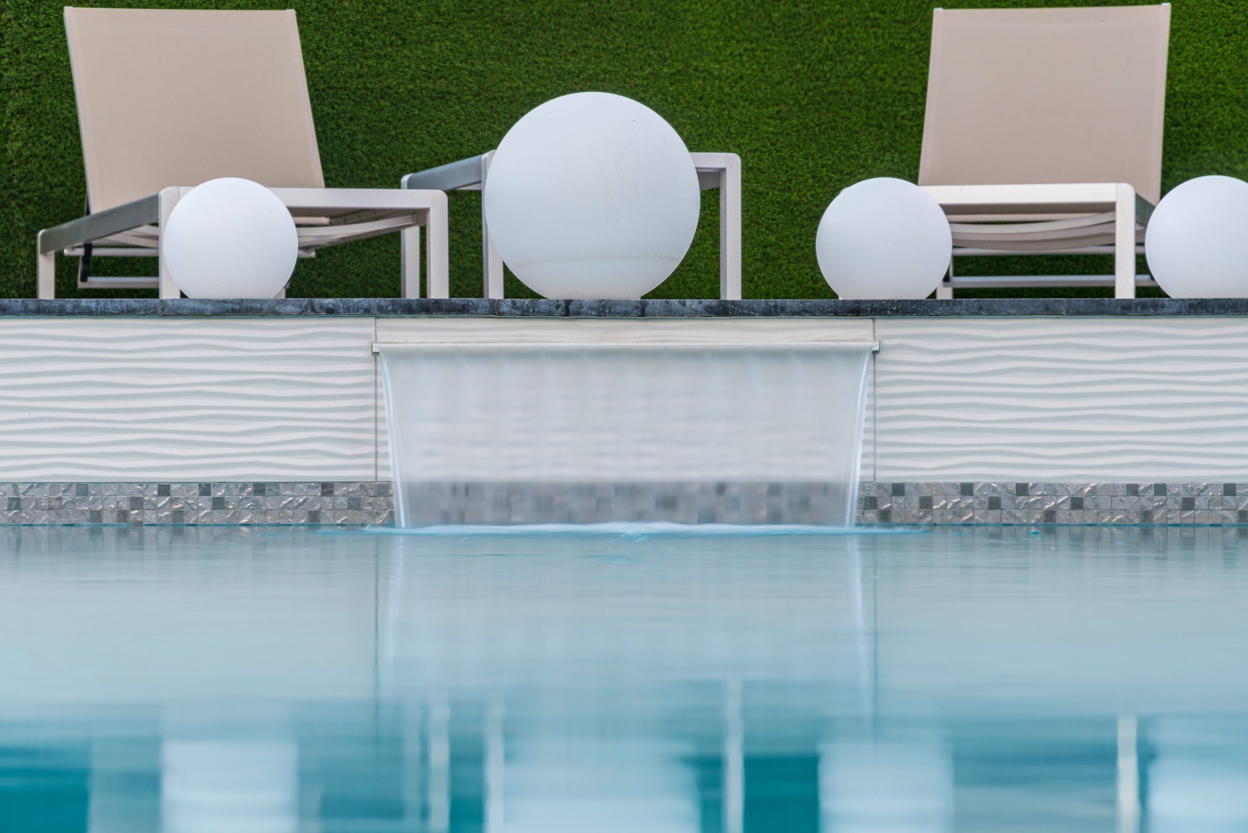 Sheer descent wall and lounge seating beside a geometric pool in Scottsdale, AZ