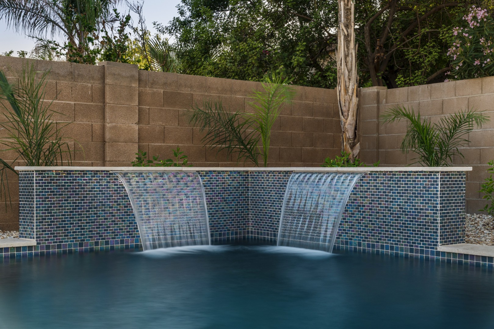 Custom freeform pool with dual waterfalls and iridescent tile in Gilbert, AZ by Envy Pools