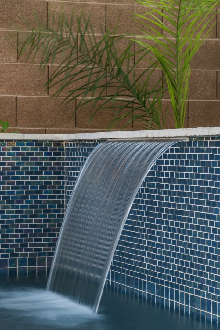 Custom freeform pool with dual waterfalls and iridescent tile in Gilbert, AZ by Envy Pools