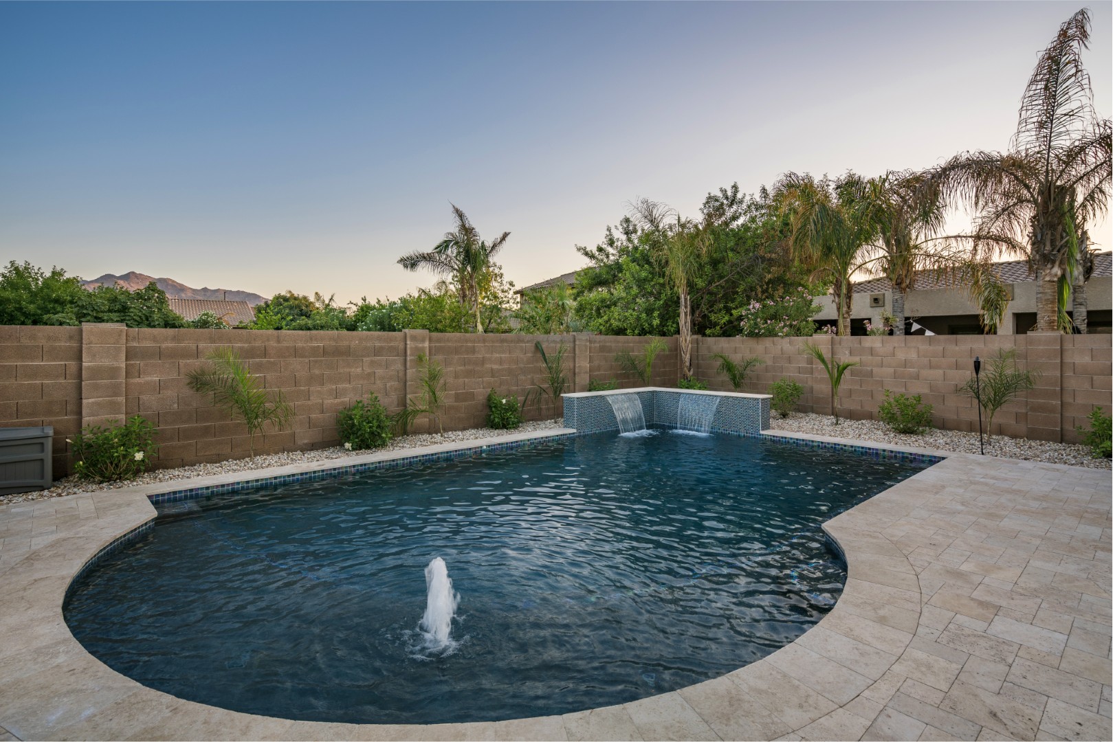 Custom freeform pool with dual waterfalls and iridescent tile in Gilbert, AZ by Envy Pools