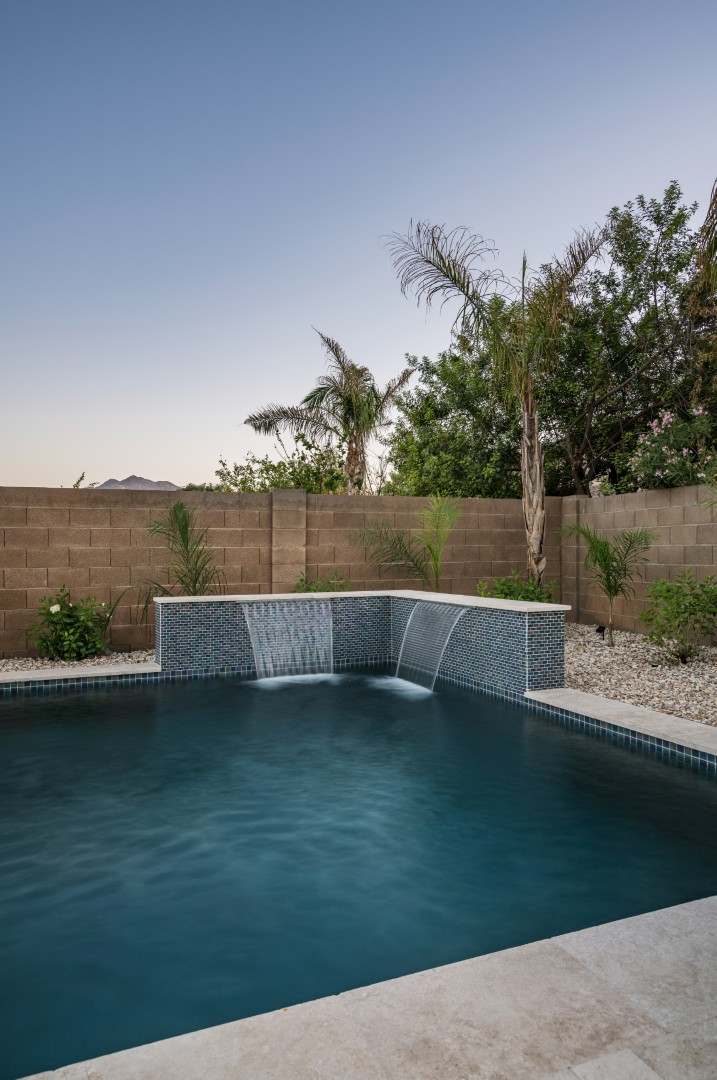 Custom freeform pool with dual waterfalls and iridescent tile in Gilbert, AZ by Envy Pools