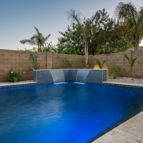 Custom freeform pool with dual waterfalls and iridescent tile in Gilbert, AZ by Envy Pools