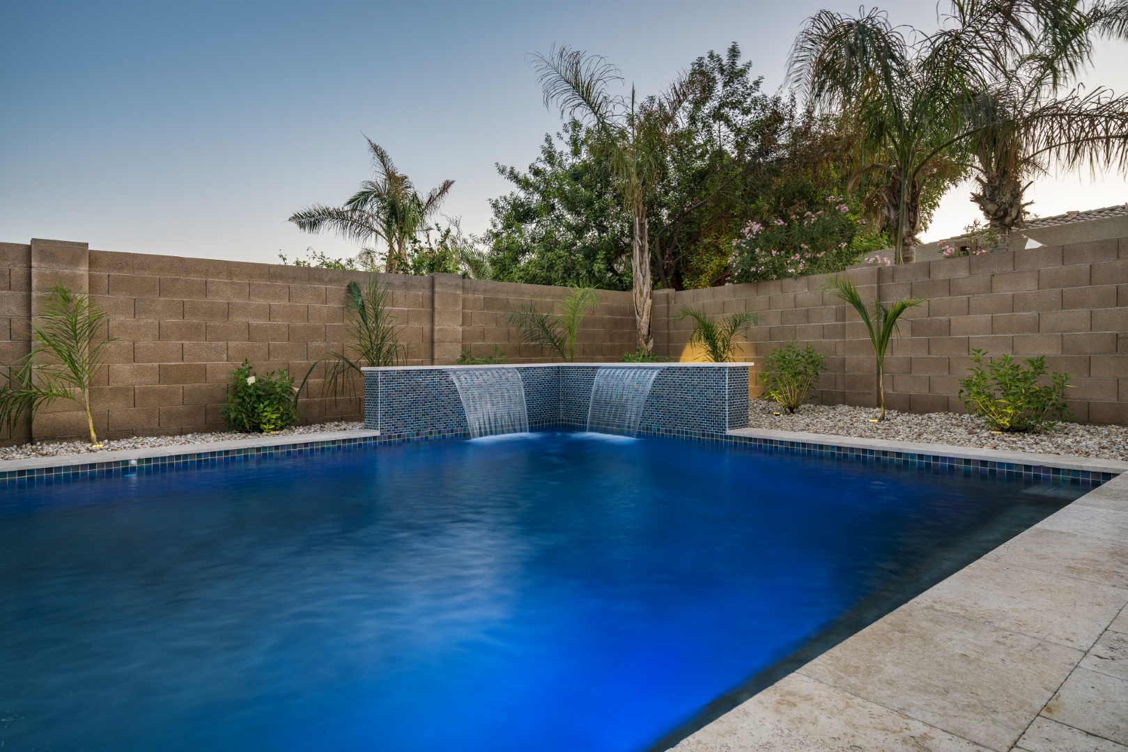 Custom freeform pool with dual waterfalls and iridescent tile in Gilbert, AZ by Envy Pools