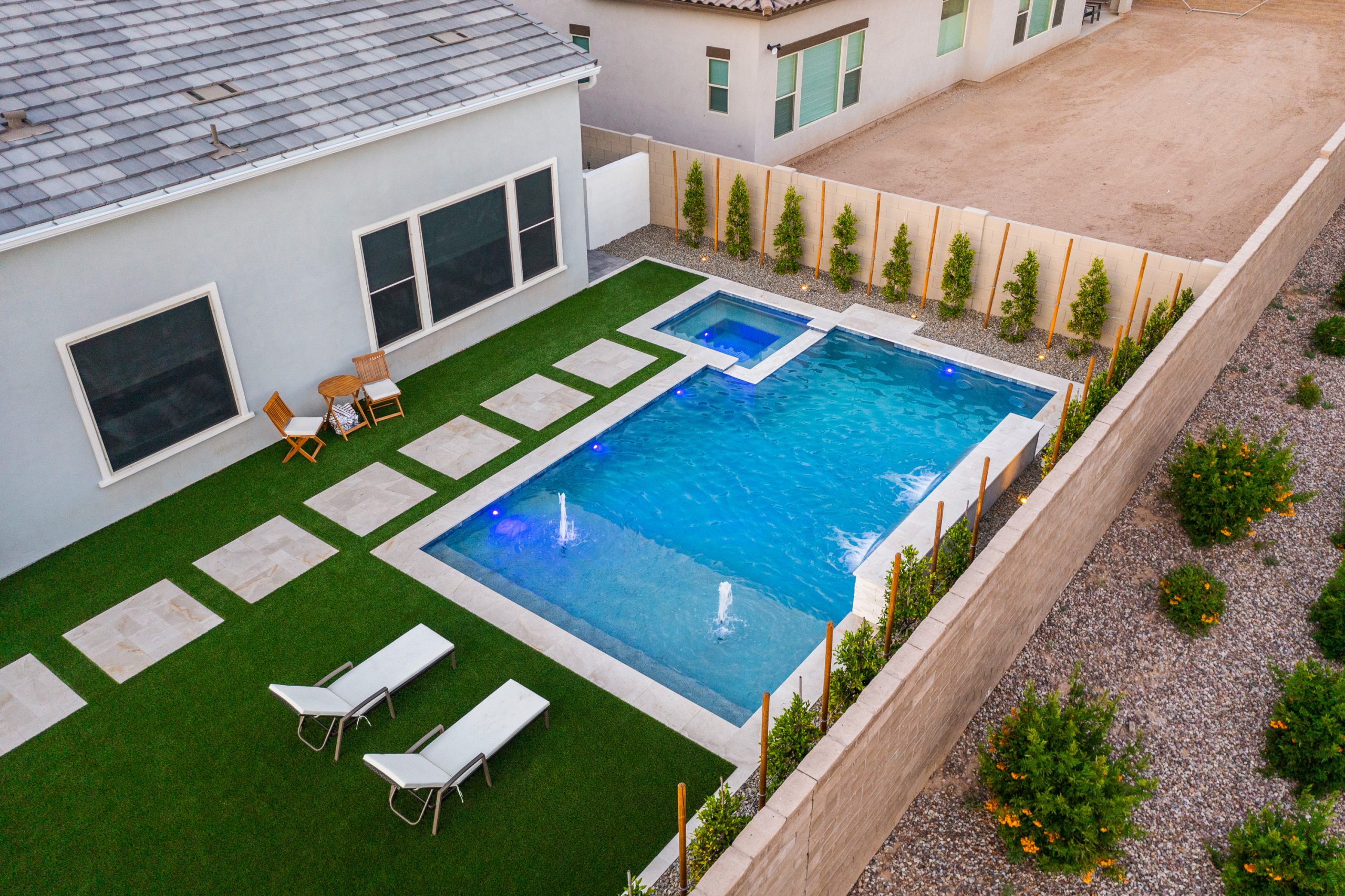 Aerial view of a lit geometric pool at dusk in Gilbert, AZ